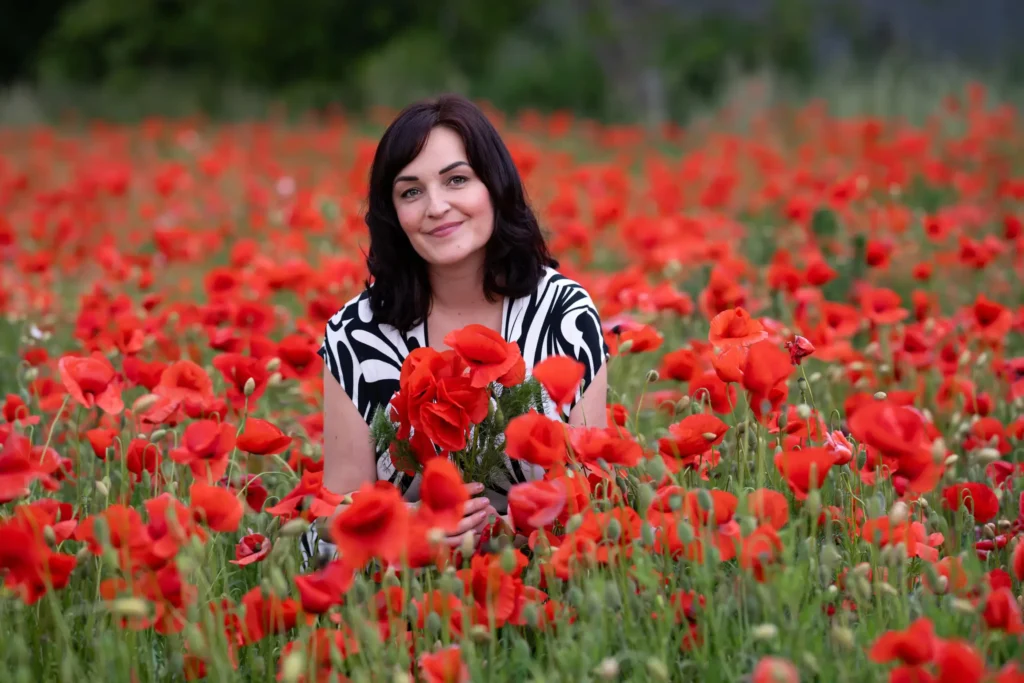 Ivana Bártková, lektorka angličtiny a majitelka jazykové školy Top English, sedí v poli plném rozkvetlých máků a usmívá se.